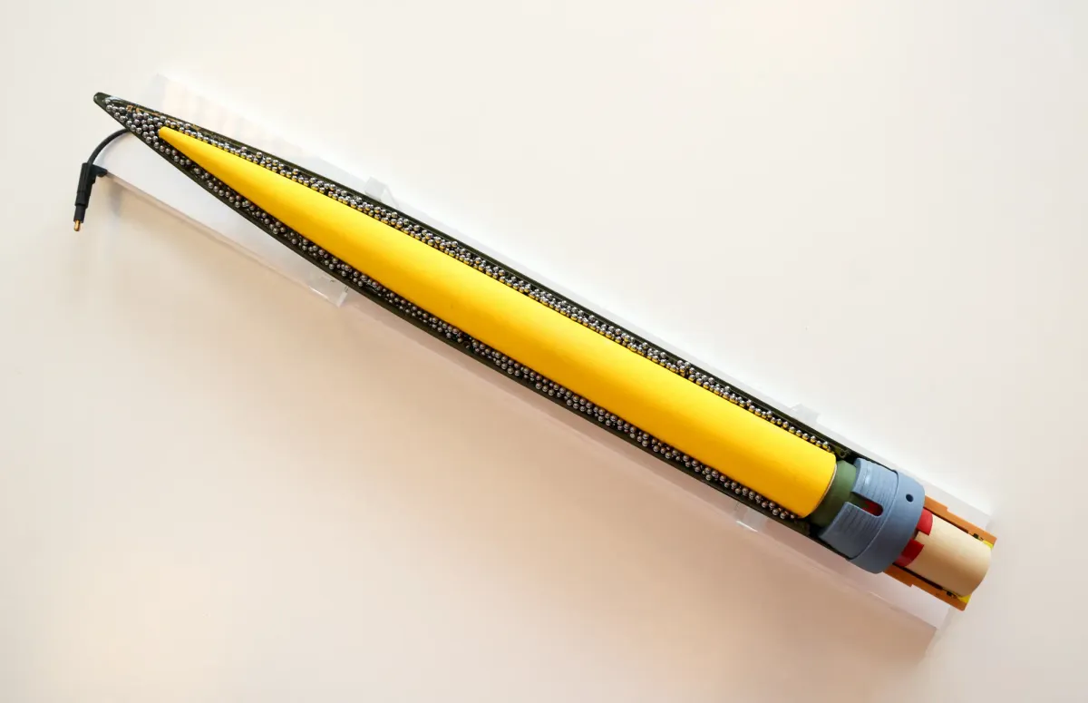 A close-up image of a yellow anti-drone rocket with a black, pointed tip and a zipper-like seam, set against a white background.