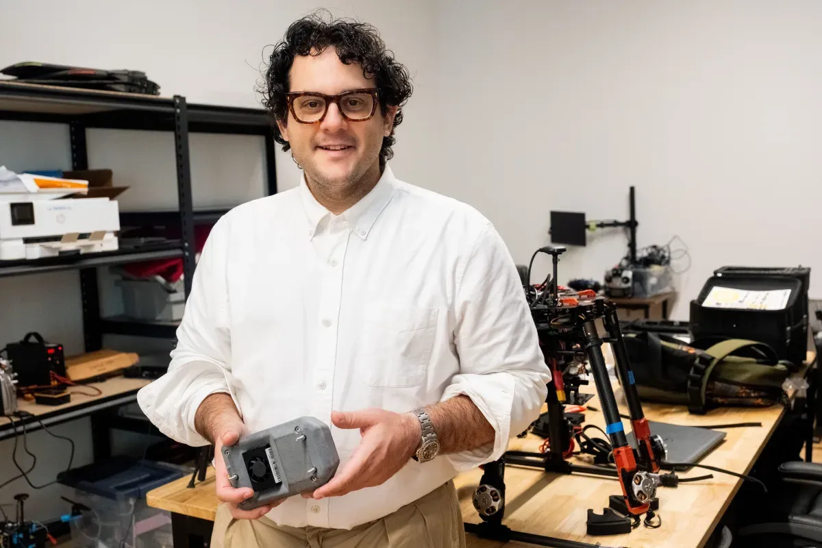 Brian Streem, founder of Vermeer, holding a device in front of drone equipment in a lab