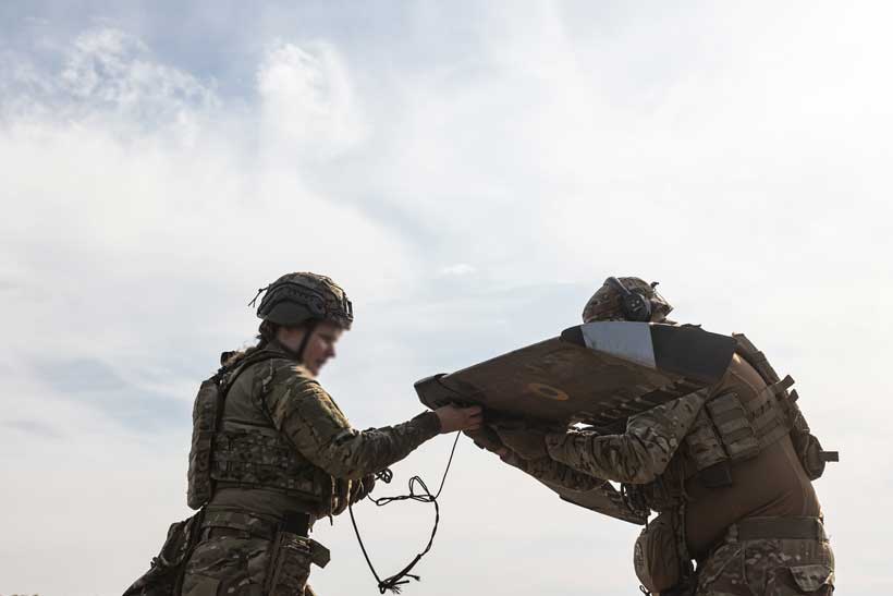 Ukrainian soldiers handling a drone, preparing for launch as part of strategy to evade Russian air defenses