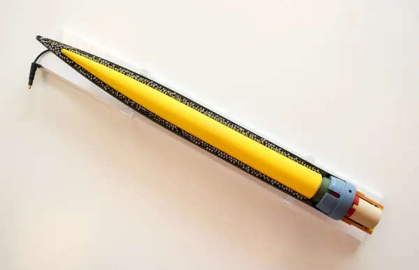A close-up image of a yellow anti-drone rocket with a black, pointed tip and a zipper-like seam, set against a white background.